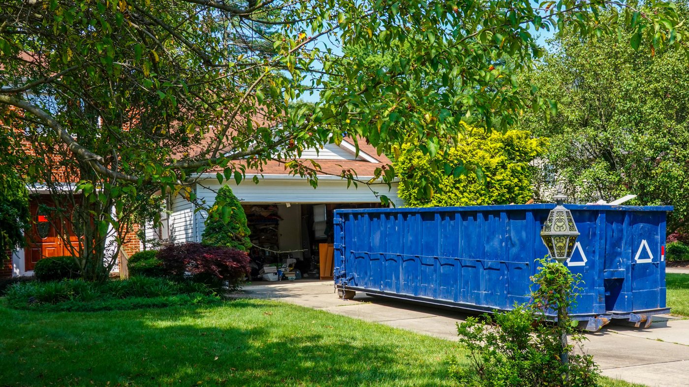 Blue roll-off dumpster delivered in a residential driveway